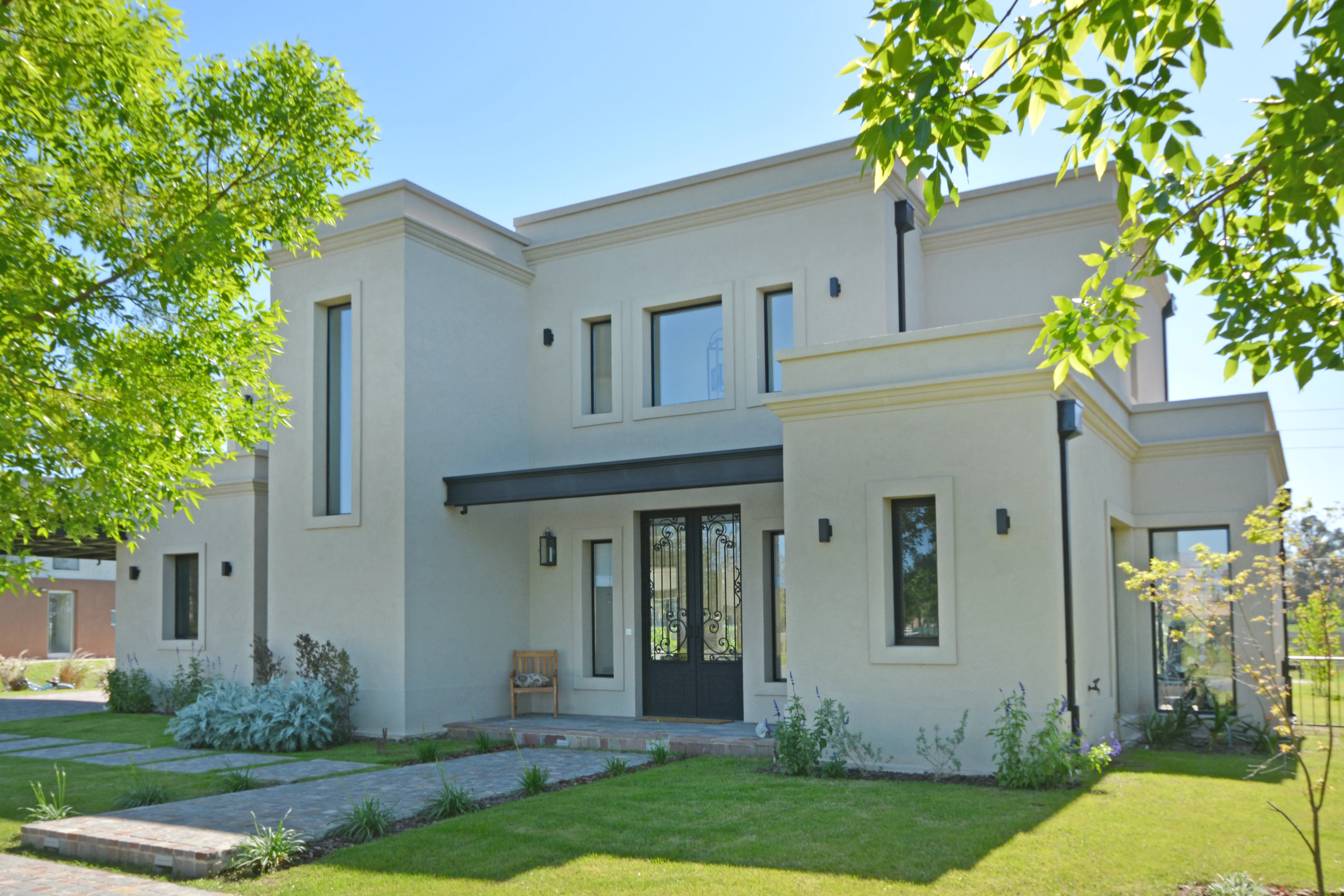 Casa de estilo clásico contemporáneo en Pilará con frente simétrico y portón de hierro forjado